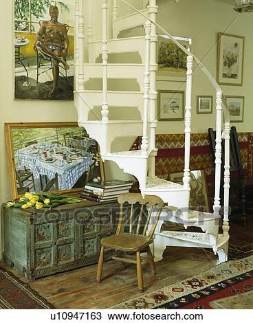 Stock Image - Painted blue chest beside white spiral staircase in traditional hall. Fotosearch