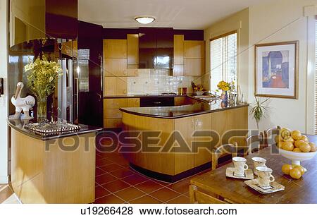 Pale wood fitted units in modern kitchen with traditional wooden table and chairs in dining area View Large Photo Image Stock Photo - Pale wood fitted units in modern kitchen with traditional wooden table and chairs in dining area. Fotosearch