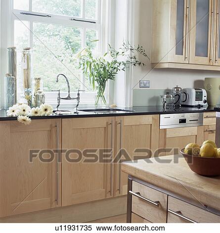 Stock Photography - Pale wood fitted units in modern townhouse kitchen. Fotosearch