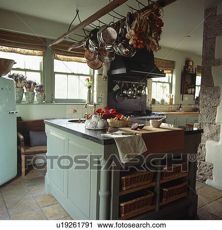 Pans on storage rack above grey-green island unit in cottage kitchen View Large Photo Image Stock Image - Pans on storage rack above grey-green island unit in cottage kitchen. Fotosearch