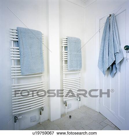 Pastel blue towels on wall-mounted radiators and the back of door in white bathroom View Large Photo Image Stock Photo - Pastel blue towels on wall-mounted radiators and the back of door in white bathroom. Fotosearch