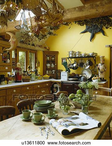 Pastel green crockery on wooden table in traditional yellow country kitchen with beamed apex ceiling View Large Photo Image Stock Image - Pastel green crockery on wooden table in traditional yellow country kitchen with beamed apex ceiling. Fotosearch