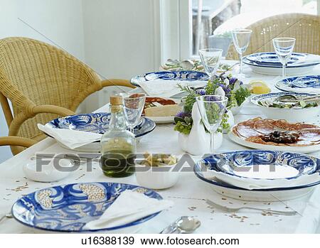 Stock Photo - Patterned blue pottery plates on white table cloth laid for lunch. Fotosearch