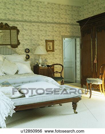 Patterned cream wallpaper in large country bedroom with blue+white checked chaiselongue at the food of the bed View Large Photo Image Stock Photograph - Patterned cream wallpaper in large country bedroom with blue+white checked chaiselongue at the food of the bed. Fotosearch