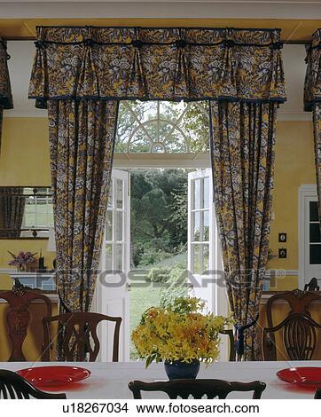 Patterned curtains with matching pelmet at open French doors in yellow country dining room View Large Photo Image Picture - Patterned curtains with matching pelmet at open French doors in yellow country dining room. Fotosearch