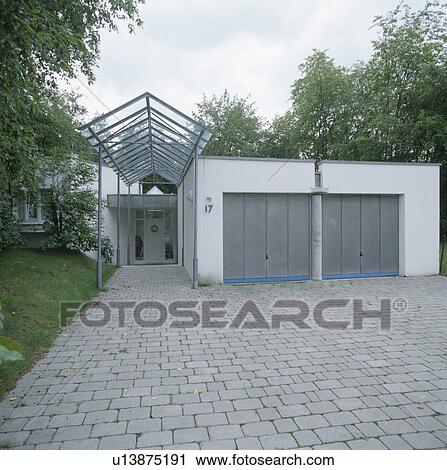 Paving in front of double garages with grey doors beside modern house View Large Photo Image Stock Image - Paving in front of double garages with grey doors beside modern house. Fotosearch