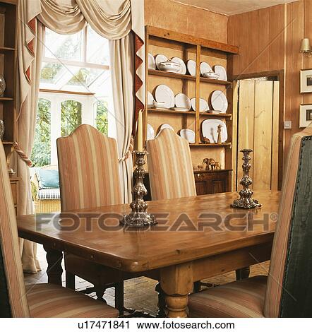 Peach-striped upholstered chairs and pine table in country dining room View Large Photo Image Stock Image - Peach-striped upholstered chairs and pine table in country dining room. Fotosearch