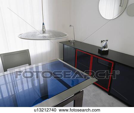Pendant disc-light above blue glass-topped table in modern dining room with black sideboard View Large Photo Image Stock Image - Pendant disc-light above blue glass-topped table in modern dining room with black sideboard. Fotosearch
