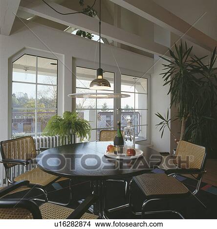 Pendant light above dark wood circular table and chrome+cane chairs in modern dining room View Large Photo Image Picture - Pendant light above dark wood circular table and chrome+cane chairs in modern dining room. Fotosearch