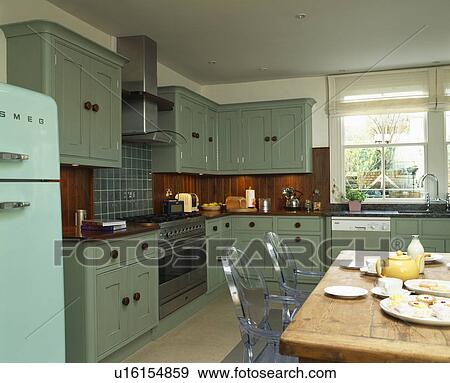 Philippe Starck Ghost chairs at old pine table in country kitchen with turquoise units View Large Photo Image Stock Photo - Philippe Starck Ghost chairs at old pine table in country kitchen with turquoise units. Fotosearch