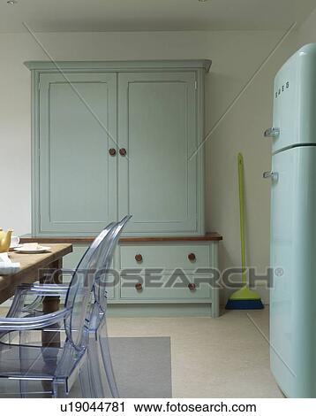 Philippe Starck Ghost chairs at table in country kitchen with turquoise dresser View Large Photo Image Stock Image - Philippe Starck Ghost chairs at table in country kitchen with turquoise dresser. Fotosearch