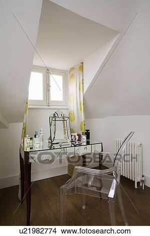 Philippe Starck perspex Ghost chair at mirrored dressing table in attic bedroom View Large Photo Image Picture - Philippe Starck perspex Ghost chair at mirrored dressing table in attic bedroom. Fotosearch