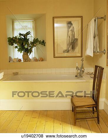 Stock Photo - Picture above bath in cream country bathroom with antique chair. Fotosearch