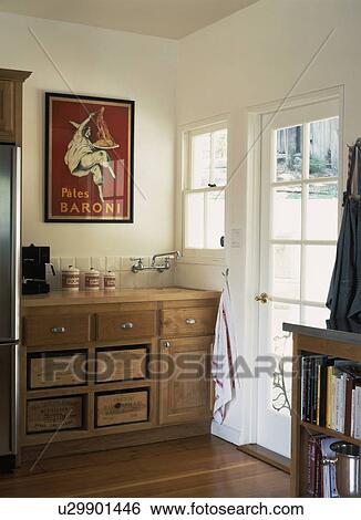 Picture on wall above sink in fitted wood unit with old wine boxes used for storage in cream kitchen View Large Photo Image Stock Photograph - Picture on wall above sink in fitted wood unit with old wine boxes used for storage in cream kitchen. Fotosearch