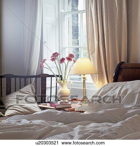 Stock Image - Pink curtains and bedlinen in small bedroom. Fotosearch