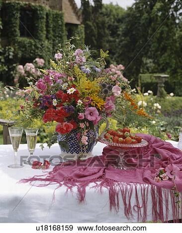 Pink fringed shawl and white linen cloth on table with vase of summer flowers in large country garden View Large Photo Image Stock Photo - Pink fringed shawl and white linen cloth on table with vase of summer flowers in large country garden. Fotosearch