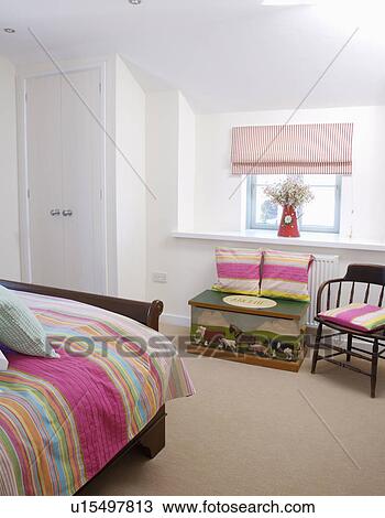 Pink striped bedlinen in white coastal cottage bedroom with cream carpet and painted wooden chest View Large Photo Image Stock Image - Pink striped bedlinen in white coastal cottage bedroom with cream carpet and painted wooden chest. Fotosearch