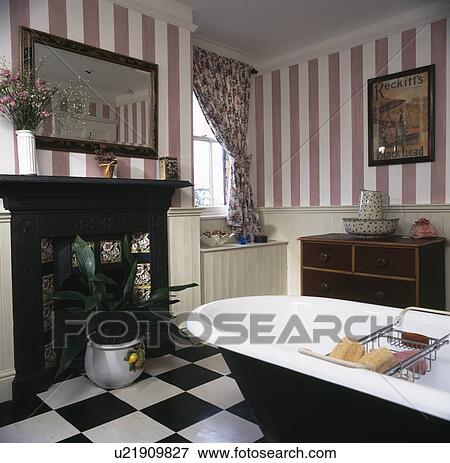 Pink striped wallpaper and rolltop bath in country bathroom with black iron fireplace View Large Photo Image Stock Photo - Pink striped wallpaper and rolltop bath in country bathroom with black iron fireplace. Fotosearch