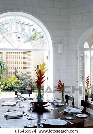 Place settings on table in dining room with large arched French doors open to small courtyard garden View Large Photo Image Picture - Place settings on table in dining room with large arched French doors open to small courtyard garden. Fotosearch