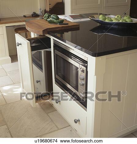 Picture - Pull-out wastebin in granite-topped island unit with fitted microwave oven. Fotosearch