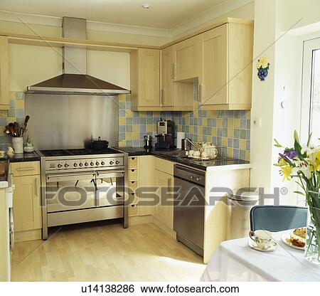 Stock Photograph - Range oven in modern kitchen with pale wood units. Fotosearch