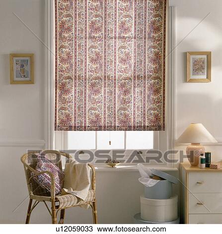 Rattan chair in front of window with pink patterned blind in bedroom with lamp on small chest-of-drawers View Large Photo Image Stock Image - Rattan chair in front of window with pink patterned blind in bedroom with lamp on small chest-of-drawers. Fotosearch