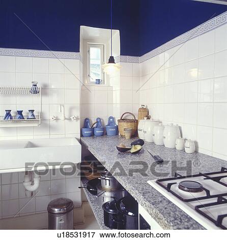 Stock Photo - Rectangular double white sink in economy-style white tiled kitchen with corian worktop. Fotosearch