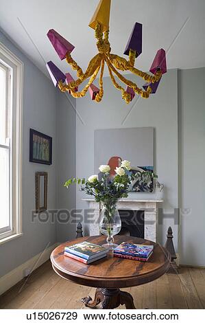 Red and yellow modern chandelier above Georgian flame mahogany veneered tripod table in grey hall View Large Photo Image Stock Photo - Red and yellow modern chandelier above Georgian flame mahogany veneered tripod table in grey hall. Fotosearch