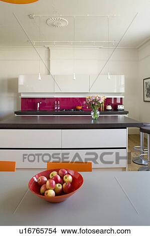 Red bowl of apples on table in modern kitchen with island unit with cast concrete resin worktop View Large Photo Image Picture - Red bowl of apples on table in modern kitchen with island unit with cast concrete resin worktop. Fotosearch