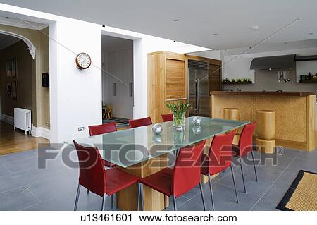Stock Image - Red chairs and glass table in large modern kitchen dining room with grey flooring. Fotosearch