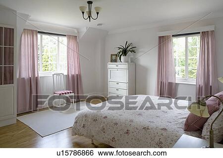 Stock Photograph - Red checked gingham curtains at windows in country bedroom with floral quilt. Fotosearch