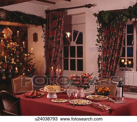 Red cloth on table set for Christmas tea in cottage dining room with Christmas tree View Large Photo Image Stock Image - Red cloth on table set for Christmas tea in cottage dining room with Christmas tree. Fotosearch