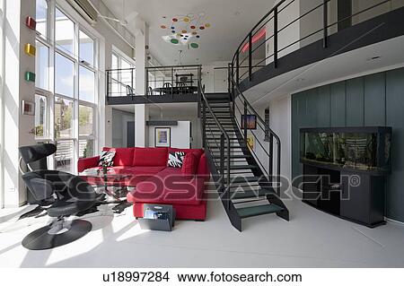 Picture - Red corner-sofa and black staircase in large open-plan living room in modern city loft conversion. Fotosearch