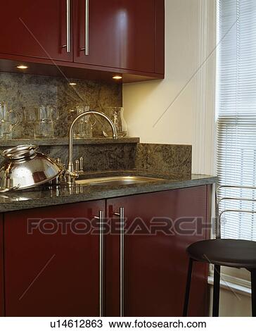 Stock Image - Red fitted units in modern townhouse kitchen. Fotosearch