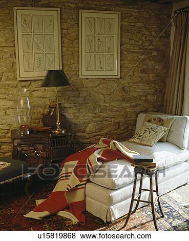 Red+cream quilted patchwork throw on white chaiselongue against exposed stone wall in country living room View Large Photo Image Stock Photo - Red+cream quilted patchwork throw on white chaiselongue against exposed stone wall in country living room . Fotosearch
