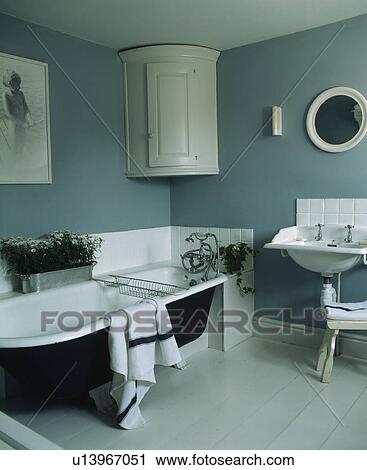 Rolltop bath and white corner cupboard in blue country bathroom View Large Photo Image Stock Image - Rolltop bath and white corner cupboard in blue country bathroom. Fotosearch