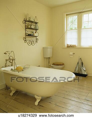 Rolltop bath in cream country bathroom with wooden flooring View Large Photo Image Stock Photo - Rolltop bath in cream country bathroom with wooden flooring. Fotosearch