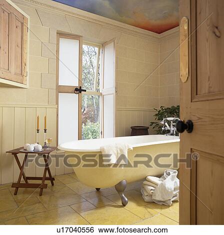 Rolltop bath in front of open French windows in white bathroom View Large Photo Image Stock Photograph - Rolltop bath in front of open French windows in white bathroom. Fotosearch