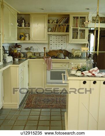 Rug on tiled floor in traditional cottage kitchen with fitted cream units View Large Photo Image Stock Photography - Rug on tiled floor in traditional cottage kitchen with fitted cream units. Fotosearch