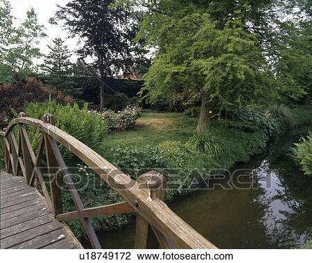 Rustic wooden bridge over stream in large country garden View Large Photo Image Stock Image - Rustic wooden bridge over stream in large country garden. Fotosearch
