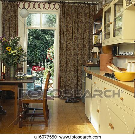 Semplice, tavola legno, e, sedie, in, cucina, con, sughero, pavimento, e, modellato, tenda, a, windows francese Archivio Immagini Semplice, tavola legno, e, sedie, in, cucina, con, sughero, pavimento, e, modellato, tenda, a, windows francese Archivio Immagini