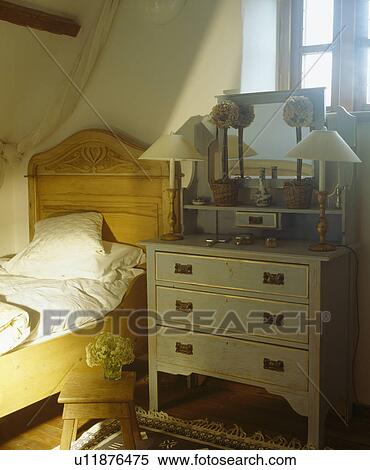 Single pine bed beside blue painted chest-of-drawers in white cottage bedroom View Large Photo Image Stock Photography - Single pine bed beside blue painted chest-of-drawers in white cottage bedroom. Fotosearch