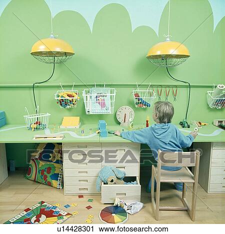 Small boy sitting at desk in playroom with green mural View Large Photo Image Stock Image - Small boy sitting at desk in playroom with green mural. Fotosearch