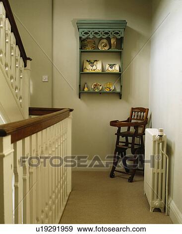 Small green shelves on wall of traditional cream landing with childs antique highchair View Large Photo Image Stock Photo - Small green shelves on wall of traditional cream landing with childs antique highchair. Fotosearch