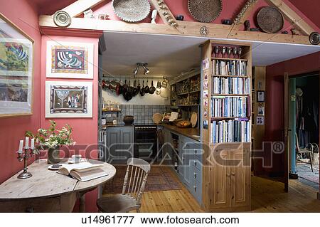 Stock Photo - Small table in open-plan hall and kitchen in country cottage . Fotosearch