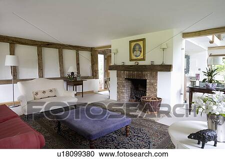 Small white sofa and blue velour stool in white living room in country barn conversion View Large Photo Image Stock Image - Small white sofa and blue velour stool in white living room in country barn conversion. Fotosearch