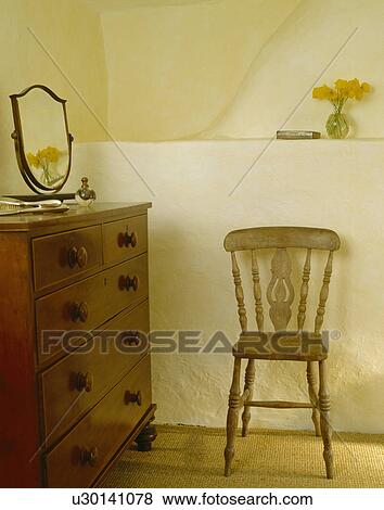 Small wooden chair and antique mahogany chest of drawers in cottage bedroom View Large Photo Image Stock Photo - Small wooden chair and antique mahogany chest of drawers in cottage bedroom. Fotosearch
