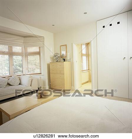 Sofa Below Bay Window Of Modern Economy Style Bedroom With Fitted