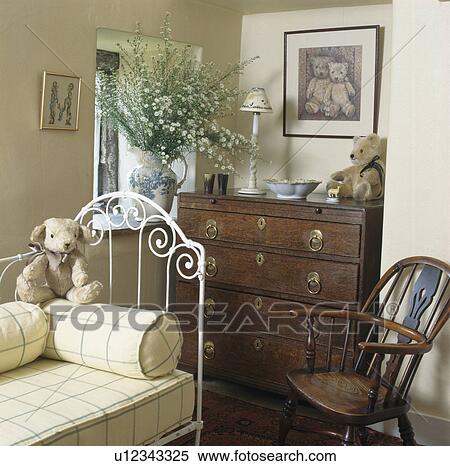 Soft toys on white iron bed in cottage bedroom with antique chest-of-drawers View Large Photo Image Stock Photography - Soft toys on white iron bed in cottage bedroom with antique chest-of-drawers. Fotosearch