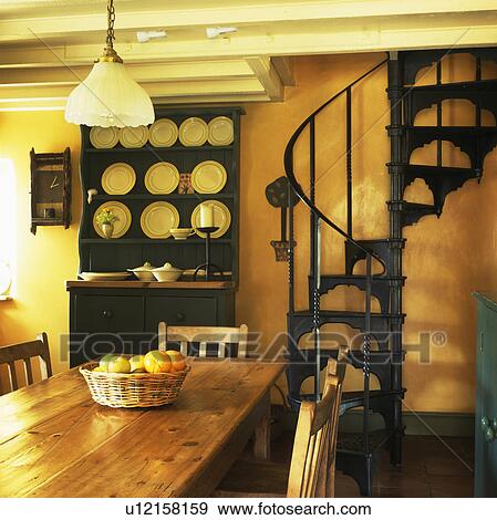 Stock Photo - Spiral staircase and green dresser in yellow cottage dining room. Fotosearch